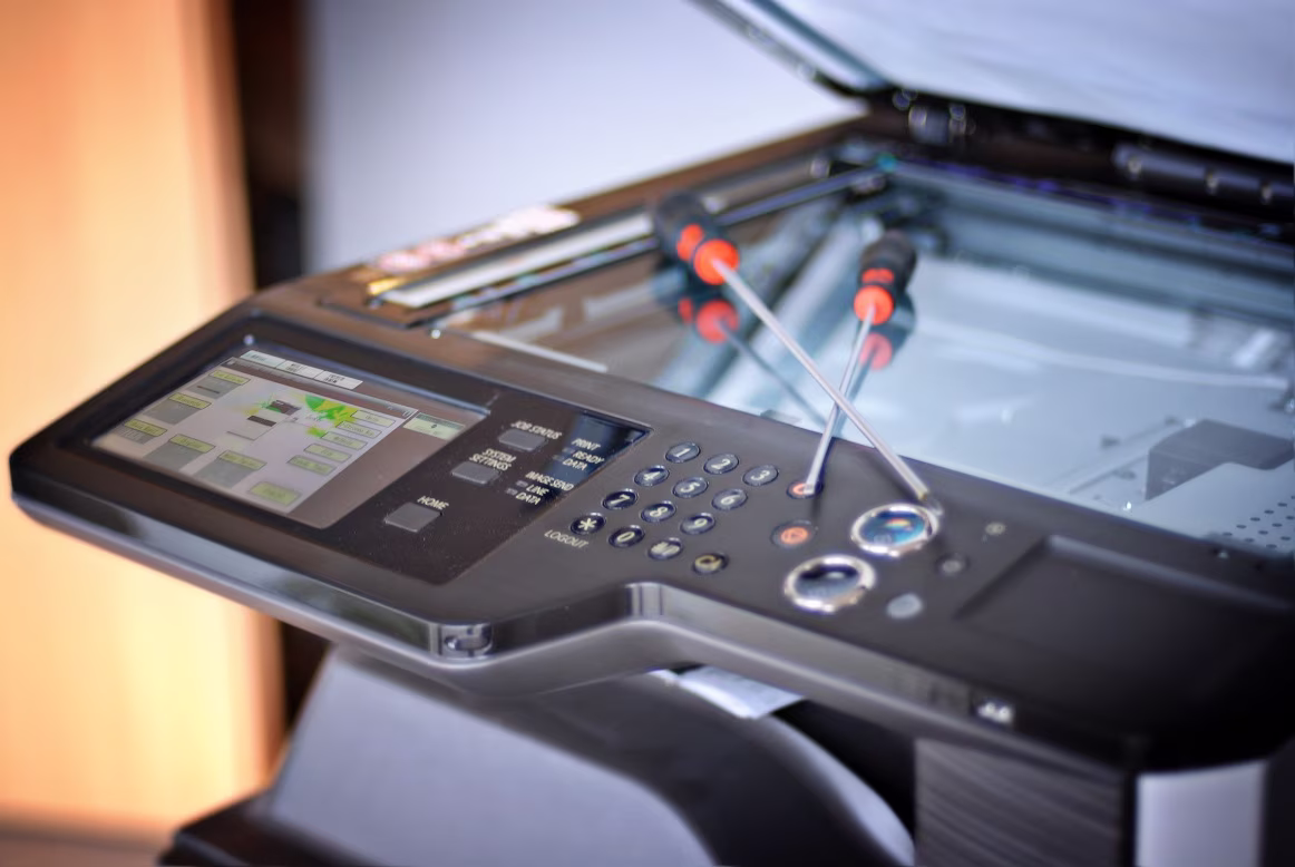 Serwisant naprawiający kserokopiarkę Sharp w biurze